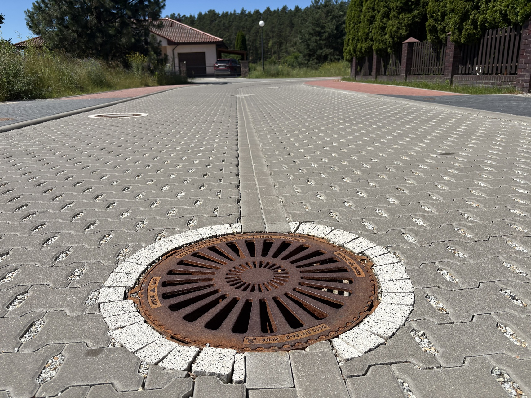 Widok studzienki kanalizacyjnej w nawierzchni z kostki brukowej.