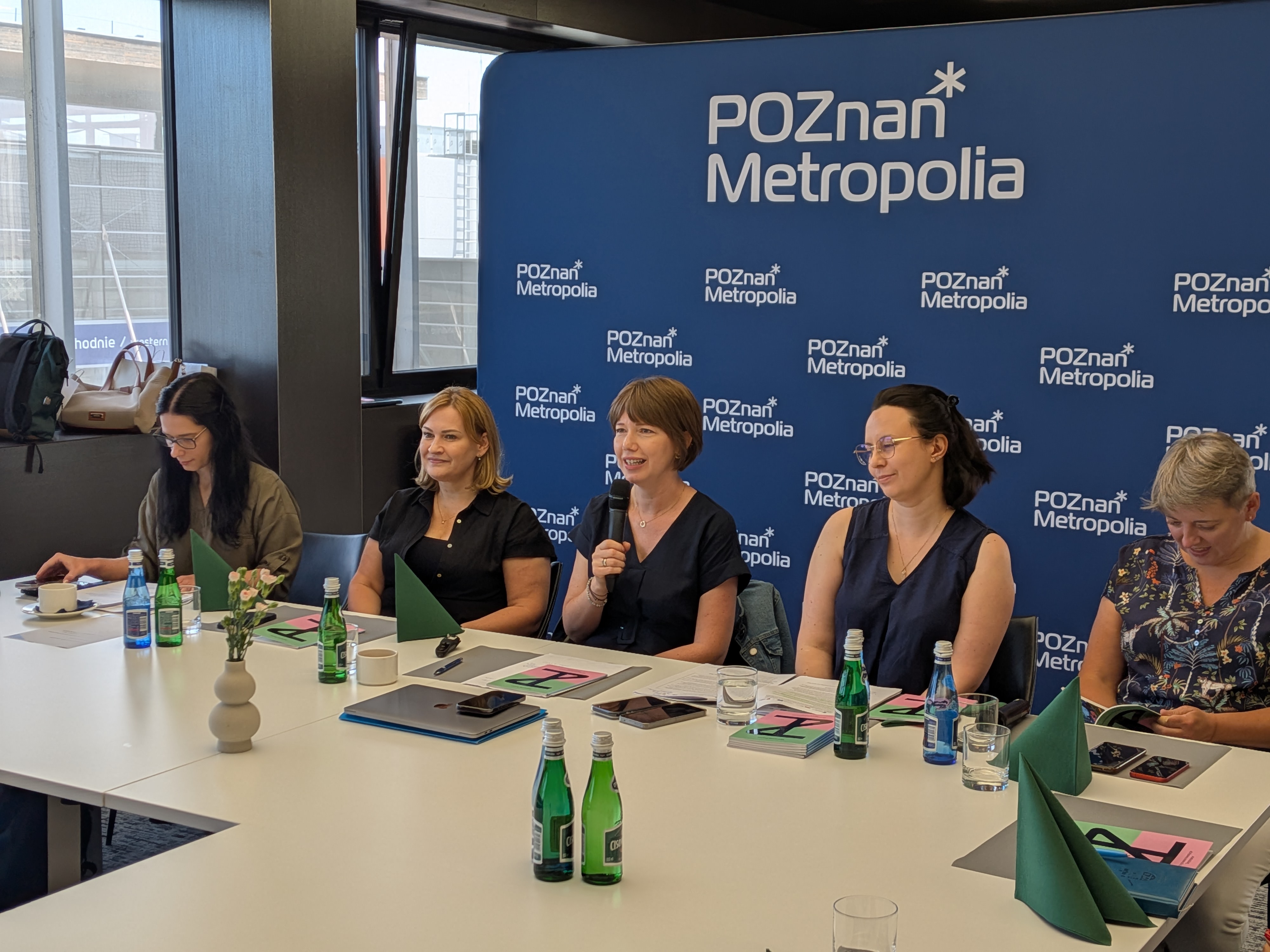Zdjęcie przedstawia kilka kobiet siedzących na tle ścianki.