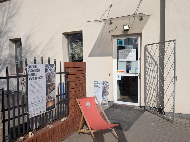 Widok wejścia do budynku - na pierwszym tle stoi leżak