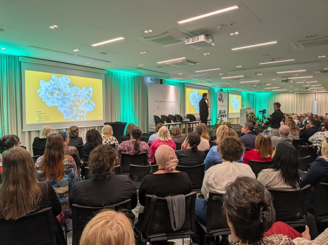 Widok sali konferencyjnej z grupą osób siedzących i zwróconych w kierunku sceny