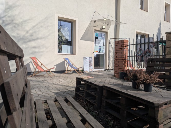 Widok wejścia do budynku - na pierwszym tle siedzisko i stolik z palet