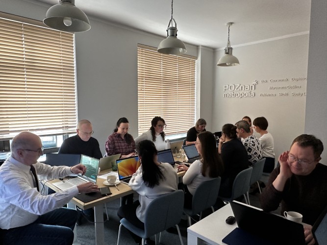 Zdjęcie przedstawia grupę osób siedzących na sali. 