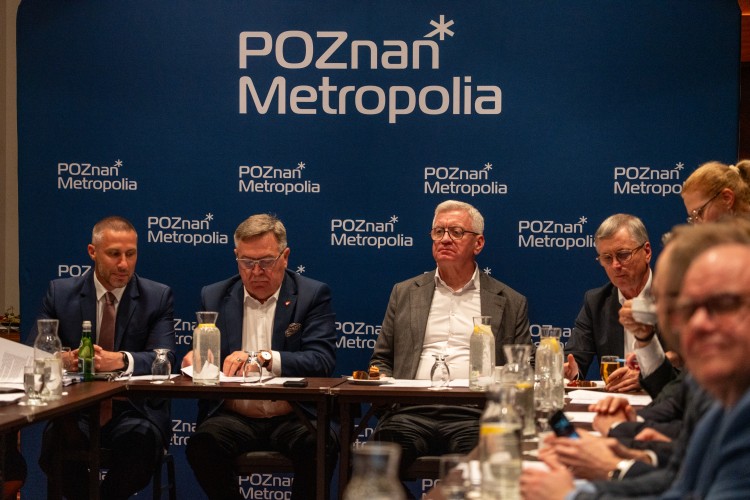 Zdjęcie przedstawia kilku mężczyzn siedzących na tle ścianki Metropolia Poznań.