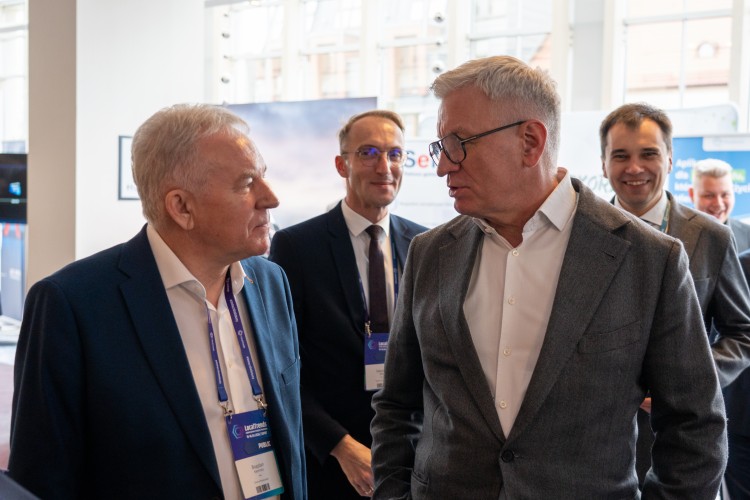 Zdjęcie przedstawia dwóch rozmawiających mężczyzn, w tle widać dwóch innych.