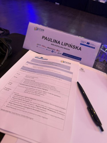 Zdjęcie przedstawia agendę wydarzenia oraz tabliczkę z imieniem i nazwiskiem uczestniczki.