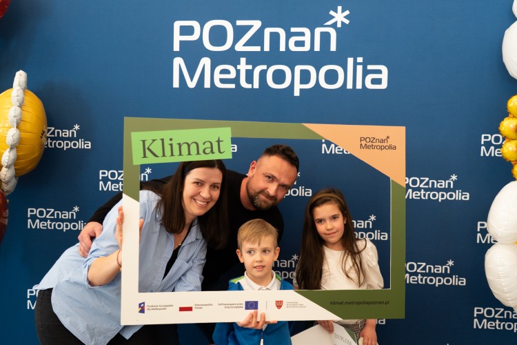 Zdjęcie przedstawia rodziców z dwójką dzieci pozujących na ściance.