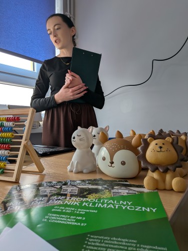 Trenerka podcza warsztatów, na pierwszym planie plakat z napisem METROPOLITALNY PIKNIK KLIMATYCZNY 