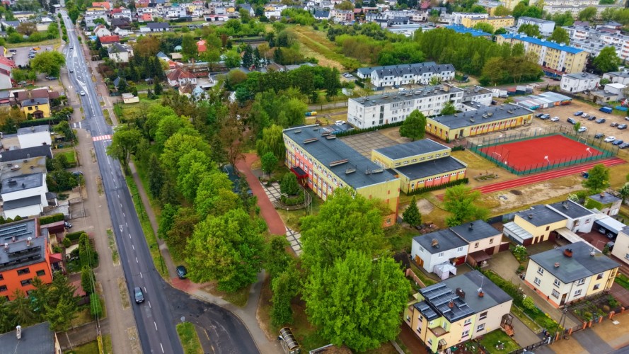 Widok szkoły z lotu ptaka, na pierwszym planie ulica i rząd drzew