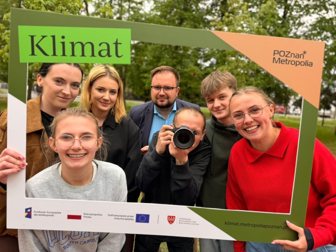 Grupa uśmiechniętych osób trzymająca instaramkę z napisem KLIMAT
