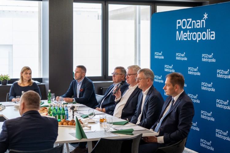 Zdjęcie przedstawia kilka osób siedzących obok siebie (włodarze gmin i miast Metropolii Poznań oraz dyrektorka Metropolii Poznań).