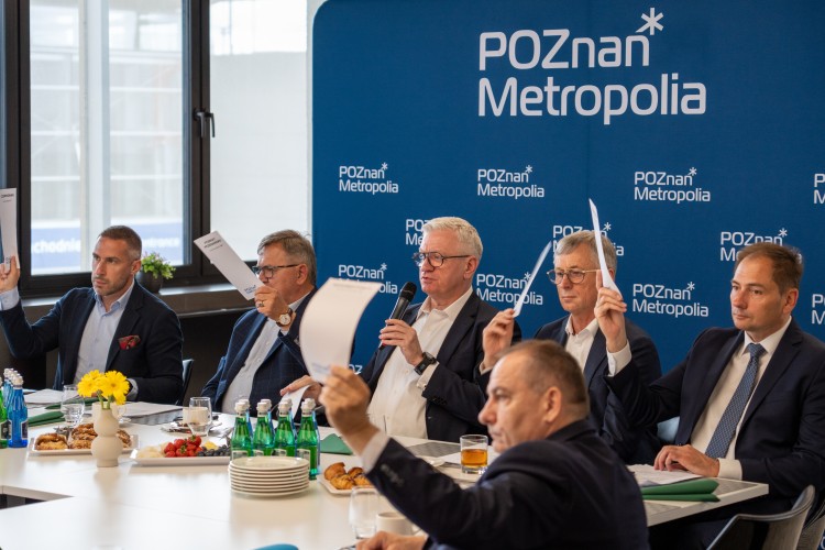Zdjęcie przedstawia kilku mężczyzn siedzących obok siebie (włodarze gmin i miast Metropolii Poznań).