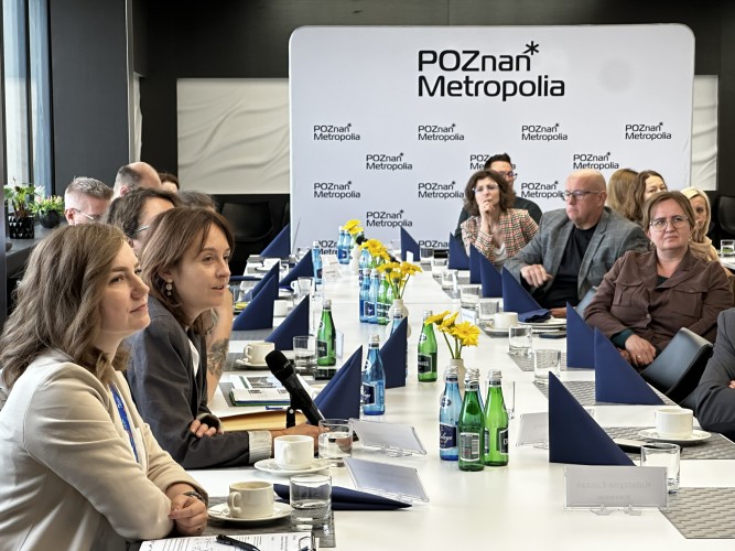 Zdjęcie przedstawia widok ludzi na sali, siedzących przy stole.