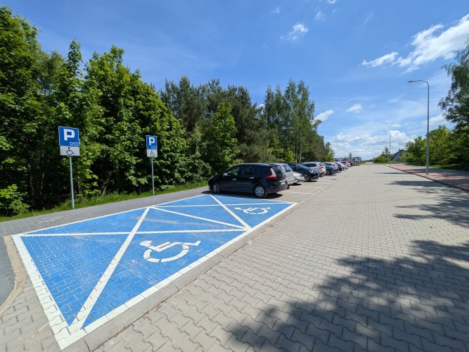 Zdjęcie przedstawiające miejsca dla niepełnosprawnych na parkingu samochodowym.