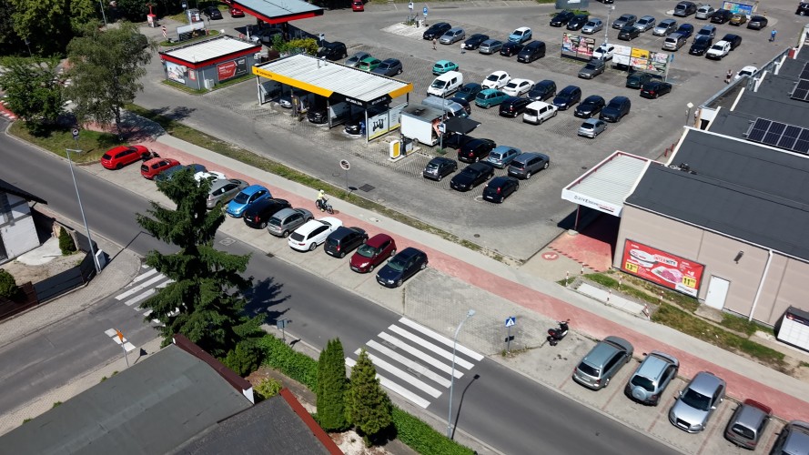 Zdjęcie z dronu przedstawiające parking samochodowy oraz myjnię samochodową.