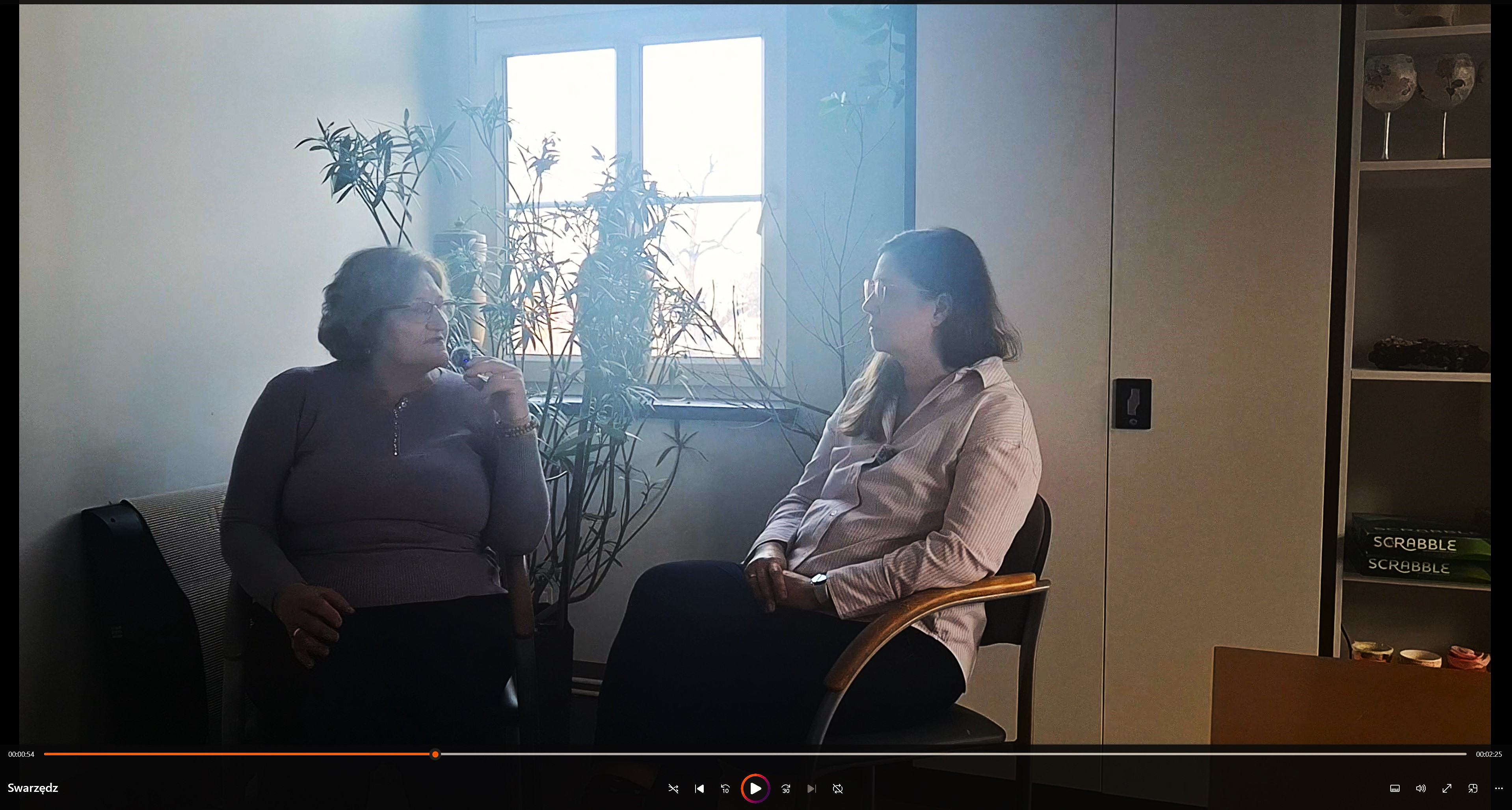 Zdjęcie przedstawia dwie osoby podczas wywiadu. W tle jasne okno.